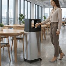 Load image into Gallery viewer, HLS Commercial HLS24DPO stainless steel trash can with black open-top lid and wheels in a modern office cafeteria.